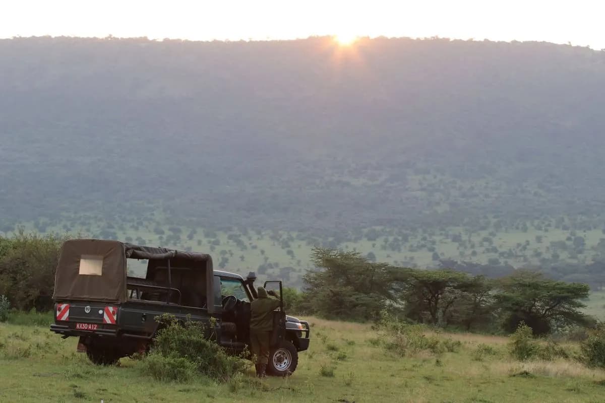 An open safari vehicle on the plains at last light